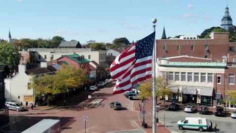 Nahaufnahme-Einer-US-amerikanischen-Flagge,-Die-über-Der-Hauptstraße-Und-Dem-State-House-Weht,-Als-Einspielaufnahme