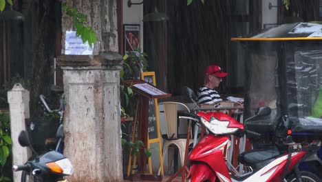 Male-Tourist-Resting-at-a-Cafe-During-the-Rain