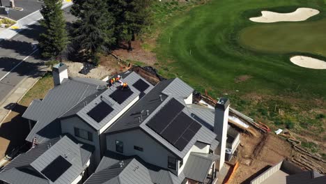 Workers-installing-large-sections-of-solar-panels-on-new-home-roof