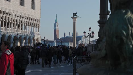 Reveal-Shot-of-Tourism-Walking-Towards-St-Marks-Bell-Tower-and-Lion-on-Column-in-Piazza-San-Marco-Venice