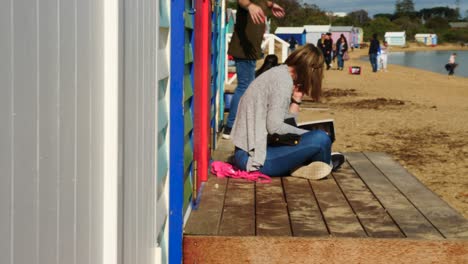 Girl-reading-Book-at-Brighton-Bathing-Boxes,-Melbourne,-Australia