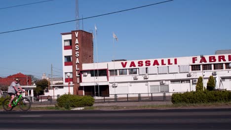 Un-Camión-Se-Mueve-De-Derecha-A-Izquierda-Por-La-Ruta-Nacional-33,-Frente-A-La-Planta-Del-Fabricante-De-Cosechadoras-Vassalli,-Mientras-Una-Bicicleta-Va-En-Sentido-Contrario