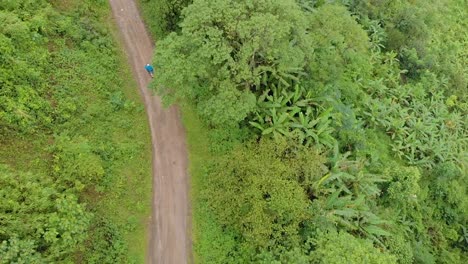 Aerial-shot-of-an-Indian-male-riding-through-the-mountains-route-in-a-remote-village,-Tamei,-Manipur,-India