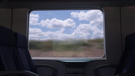 View-of-countryside-on-sunny-summer-day-through-silhouetted-train-window