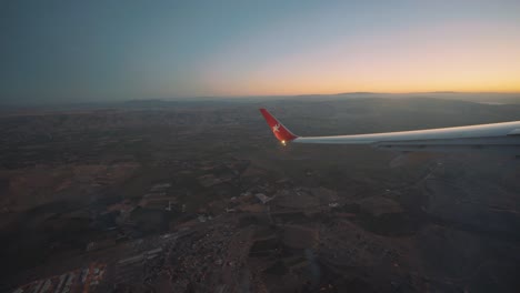 Airplane-window-view-of-the-planes-left-wing-while-taking-a-turn,-golden-hour