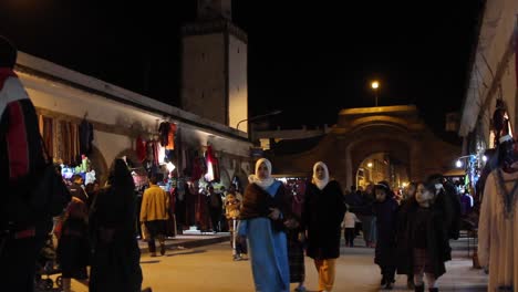 Street-view-of-local-men-and-women-shopping-in-Essaouira,-Morocco-at-night
