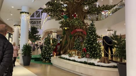 Weihnachtsbaum-Im-Einkaufszentrum,-Kinder-Spielen-Zwischen-Den-Weihnachtsdekorationen,-Menschen-Gehen-Spazieren-Und-Kaufen-Ein