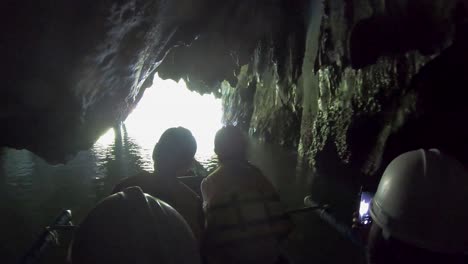 People-in-lifejackets-and-helmets-swim-on-a-boat-through-a-dark-cave