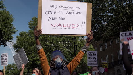 Ein-Demonstrant-Mit-Schutzmaske-Hält-Ein-Plakat-Hoch,-Auf-Dem-Steht:-„540-Kollegen-Sind-An-Covid-19-Erkrankt-Und-Wir-Werden-Nicht-Wertgeschätzt.“