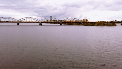Hyperlapse-of-cargo-train-transporting-wagons-across-the-iron-train-bridge-in-downtown-of-Rige-city,-Latvia