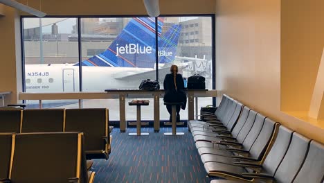 Mujer-Sentada-Y-Mirando-Por-La-Ventana-En-El-Aeropuerto-Internacional-Logan-De-Boston-Durante-La-Pandemia-De-Coronavirus