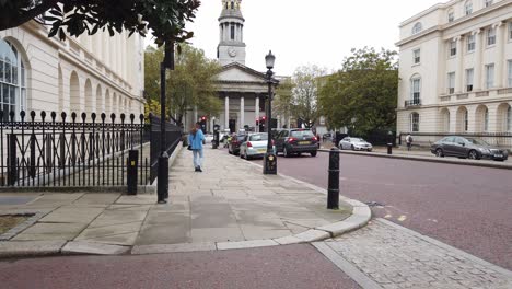 London-street-handheld-footage-car-drives-by-girl-standing-in-street-then-man-in-running-gear-walks-past