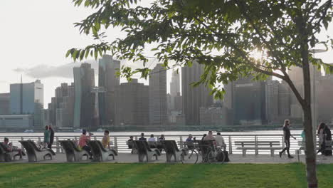 People-relaxing-at-Gantry-Plaza-State-Park,-Manhattan-skyline
