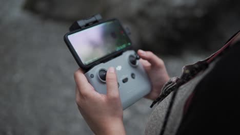 Close-Up-of-DJI-Drone-Controller-and-Smartphone-as-Monitor-in-Hands-of-Female