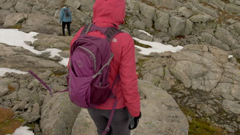Two-Women-Hiking-Over-Rocky-and-Snowy-Terrain-on-a-Cold,-Overcast-Day-in-Norway