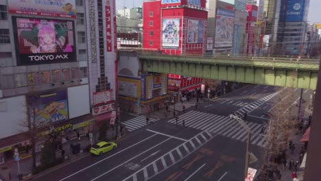 High-angle-establishing-pan-looking-over-neon-signs,-shopping-centers-and-raised-JR-railway