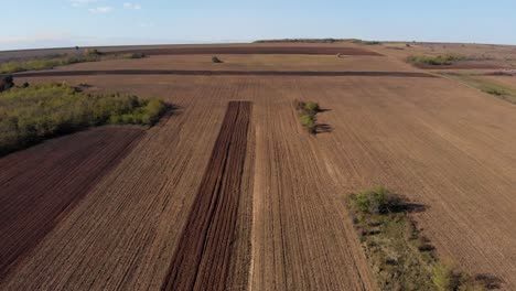 Aerial-view-over-brown-autumn-fields,-on-a-sunny,-fall-day---dolly,-drone-shot