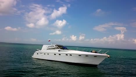 White-motor-Yacht-anchored-near-the-island-coastline-with-Indonesian-flag,-Aerial-orbit-around-shot