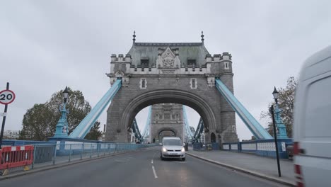 Cars-driving-off-tower-bridge-London-on-a-cloudy-day-from-centre-of-road