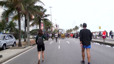 People-walking-by-the-beach-during-a-protest-in-Rio-de-Janeiro,-Brazil