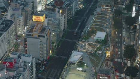 High-Angle-Top-Down-Wide-Shot-of-Trains-and-Traffics-Passing-By-at-Night-in-Shibuya,-Real-Time