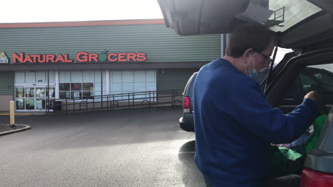 Geparkte-Fahrzeuge-Vor-Naturkosthändlern-Mit-Männlichen-Kunden,-Die-Gesichtsmasken-In-Coos-Bay,-Oregon,-Tragen