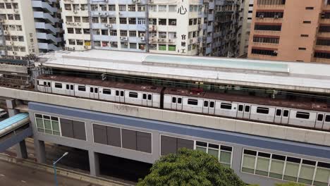 Hong-Kong-downtown-MTR-city-tram-crossing-a-bridge,-Aerial-view