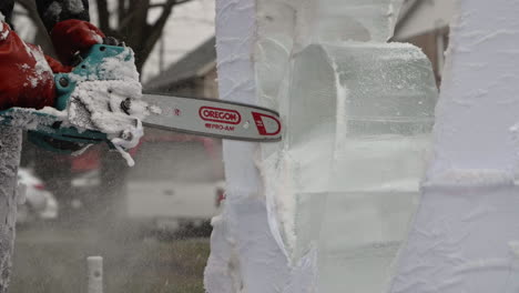 Ice-sculptor-using-electric-chainsaw-to-cut-fine-details-into-face-of-ice-blocks,-Slow-Motion