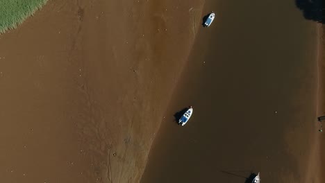 Top-down-of-boats-moored-in-a-low-tide-sandy-estuary