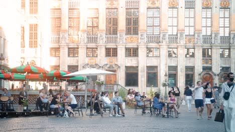 Gente-Caminando-Casualmente-Y-Disfrutando-De-Bebidas-En-Una-Noche-De-Verano-En-El-Gran-Lugar-De-Bruselas,-Bélgica,-Durante-La-Pandemia-De-Covid