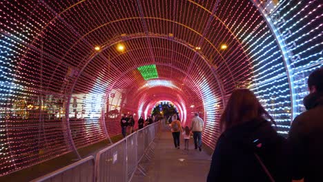 People-walk-inside-tunnel-illuminated-by-psychedelic-colored-lights,-Madeira