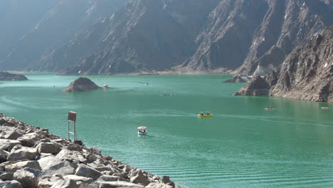 Tourists-in-colourful-pedal-boats-in-the-emerald-water,-Hatta-Dam-Lake