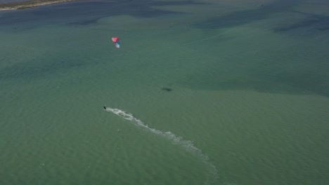 Closely-following-and-then-flying-over-Kite-Surfer-on-Green-Ocean-Waters,-Drone-Aerial,-Fuzeta