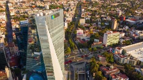 Aerial-flyover-of-Manacar-Tower-Roundabout-sunset-dusk-Traffic-in-Mexico-City,-Timelapse-from-above-the-tower