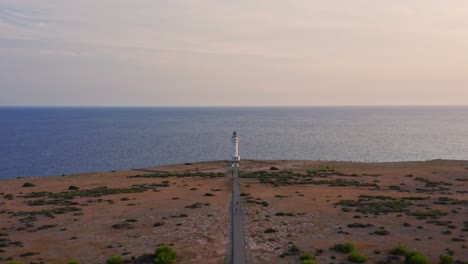 Lighthouse-cupola-dolly-in,-empty-road-in-dry-plain-and-calm-blue-sea