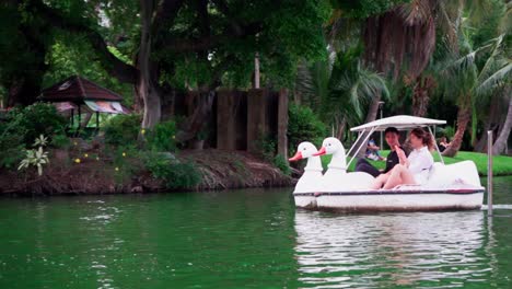 Ein-Zeitlupenclip-Eines-Jungen-Paares,-Das-Während-Der-Sozialen-Distanzierung-Auf-Einem-Paddelboot-Mit-Weißem-Schwimmmotiv-In-Bangkok-Fährt