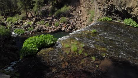 River-aerial-reveals-swimmers-in-pool-below-beautiful-McCloud-Falls