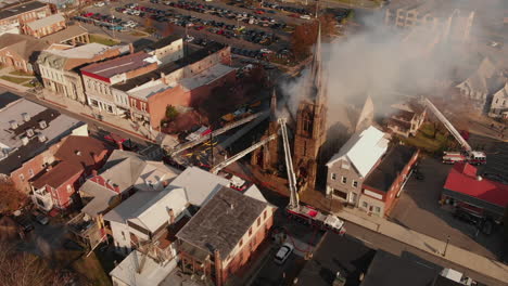 Bomberos-Entrando-En-Una-Iglesia-En-Llamas-En-Un-Pequeño-Pueblo,-Aéreo,-A-Cámara-Lenta