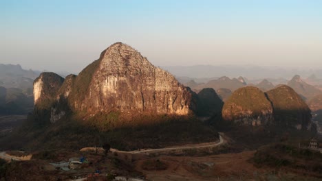 Aerial-shot-of-a-huge-mountain,-lit-up-but-the-sunset-sun