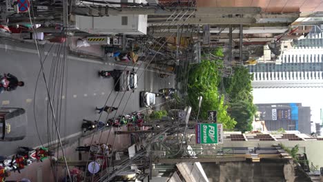 Vertikales-Video-–-Eine-Ansicht-Von-Motorradtaxifahrern,-Die-In-Der-Warteschlange-Warten,-Während-Der-Verkehr-Stetig-Fließt,-Und-Von-Fußgängern,-Die-Die-Soi-Saladaeng,-Bangkok,-Thailand,-überqueren