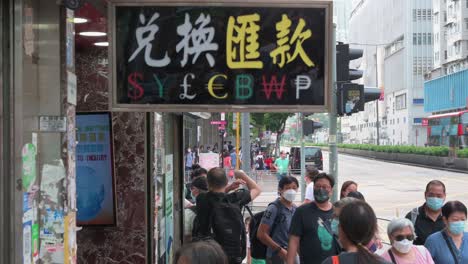 Pedestrians-walk-past-a-currency-money-exchange-shop-with-a-sign-offering:-US-Dollar-