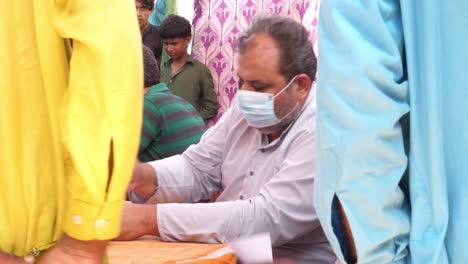 Helfer-Mit-Gesichtsmaske-Helfen-Einem-Flüchtling-In-Pakistan,-Sein-Zelt-Zu-überfluten