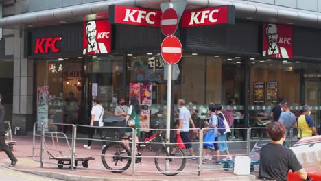 Asiatische-Fußgänger-Gehen-Auf-Einer-Belebten-Straße-In-Hongkong-An-Der-Amerikanischen-Multinationalen-Fast-Food-Restaurantkette-Kentucky-Fried-Chicken-Vorbei