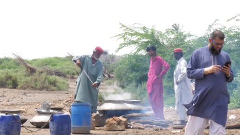 Paquistaníes-Masculinos-Cocinando-Comida-Fresca-Caliente-En-Una-Olla-De-Metal-En-El-Campamento-De-Ayuda-Contra-Inundaciones-En-Sindh