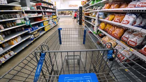 POV-while-pushing-a-cart-past-partially-empty-shelves-meant-for-snack-foods-and-breakfast-foods