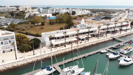 Centro-De-Marina-De-Lagos-En-La-Bahía-De-Lagos-Con-Barcos-Anclados-En-Faro,-Algarve,-Portugal--órbita-Aérea-De-ángulo-Bajo