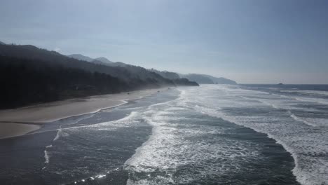 Intense-sunshine-reflecting-off-a-pristine-beach-along-the-Oregon-coast,-aerial-dolly