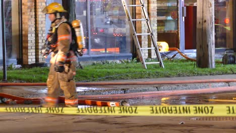 Feuerwehrmann-Entleert-Den-Feuerlöschschlauch-Auf-Der-Straße-Hinter-Dem-Notfallband