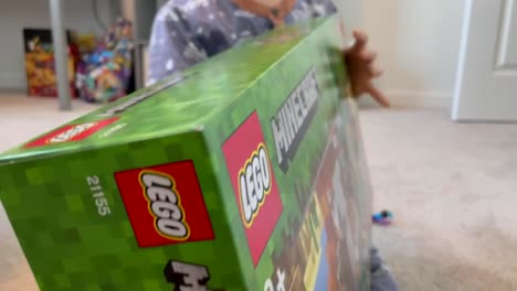 Unidentifiable-boy-in-pajamas-holding-up-a-brand-new-LEGO-MINECRAFT-Building-Set-he-got-for-Christmas