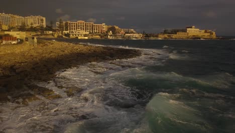 Resorts-Und-Andere-Gebäude-Entlang-Des-Strandes-Erstrahlen-In-Goldenem-Glanz,-Wenn-Sie-In-Malta-Von-Der-Morgensonne-Beleuchtet-Werden